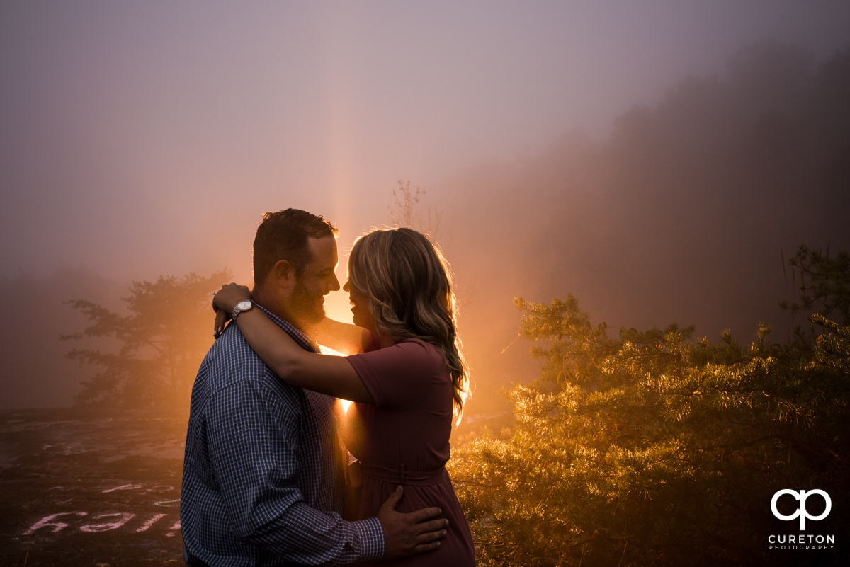 Backlit photo of an engaged couple in the fog.