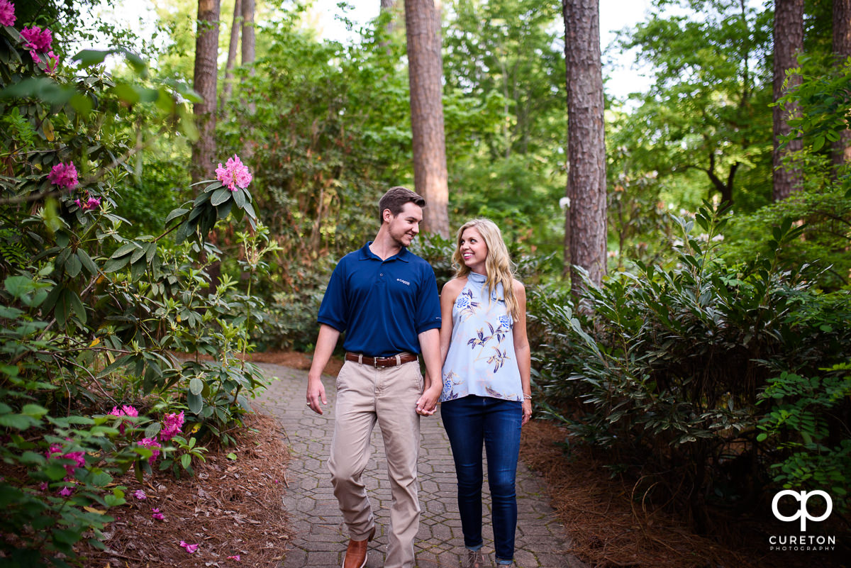 Couple holding hands walking down a trail at the Botanical Gardens in Clemson.