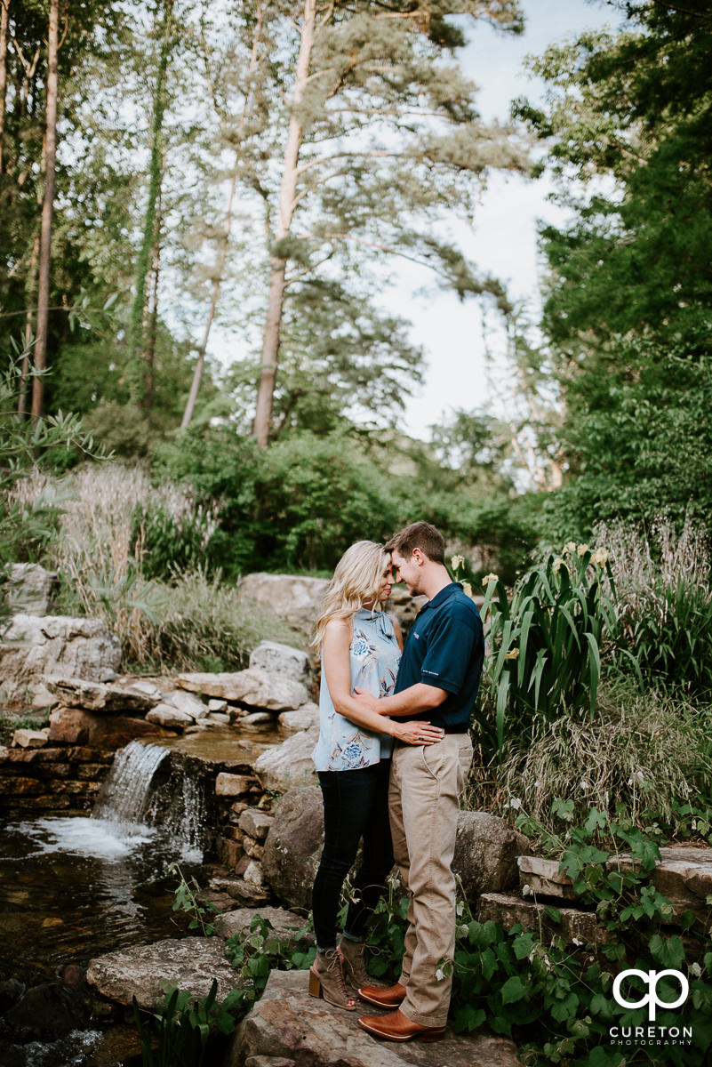 Engaged couple standing in a stream at their Botanical Garden engagement session.