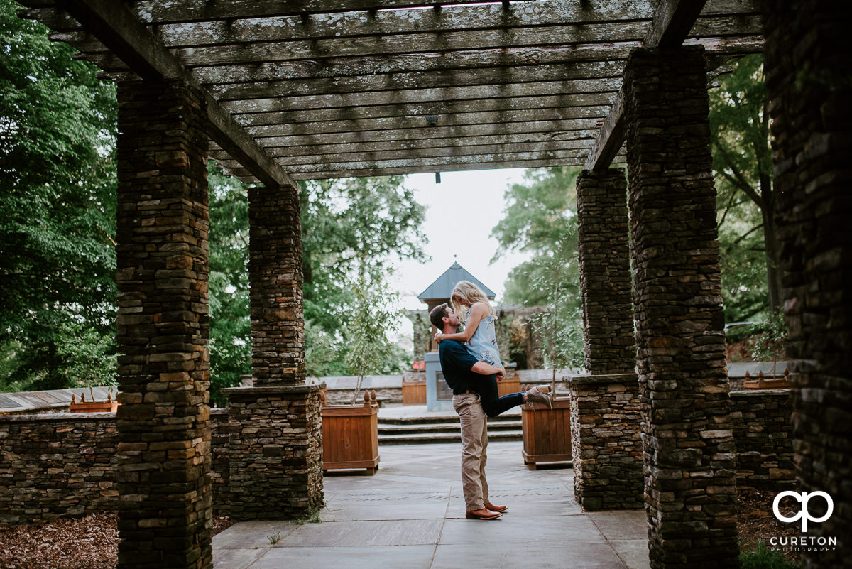 Man holding his fiancee in the air during their engagement session.