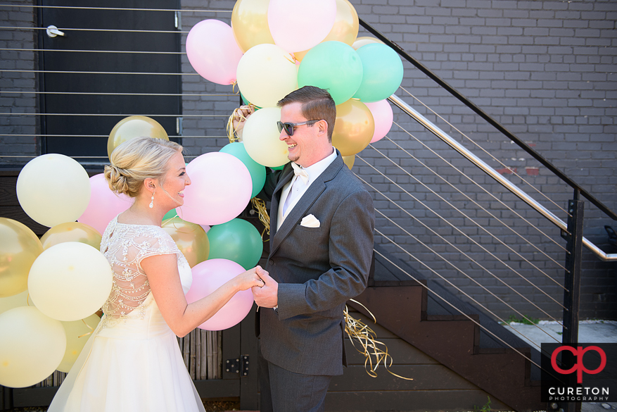 Bride and groom both holding balloons.
