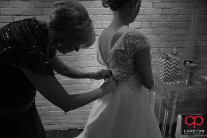 Bride's mom helps her in the dress.