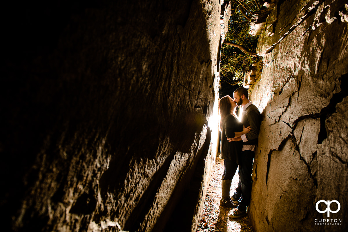 Bride and groom kissing inside of Devils Kitchen during their engagement session at Caesar's Head State Park.
