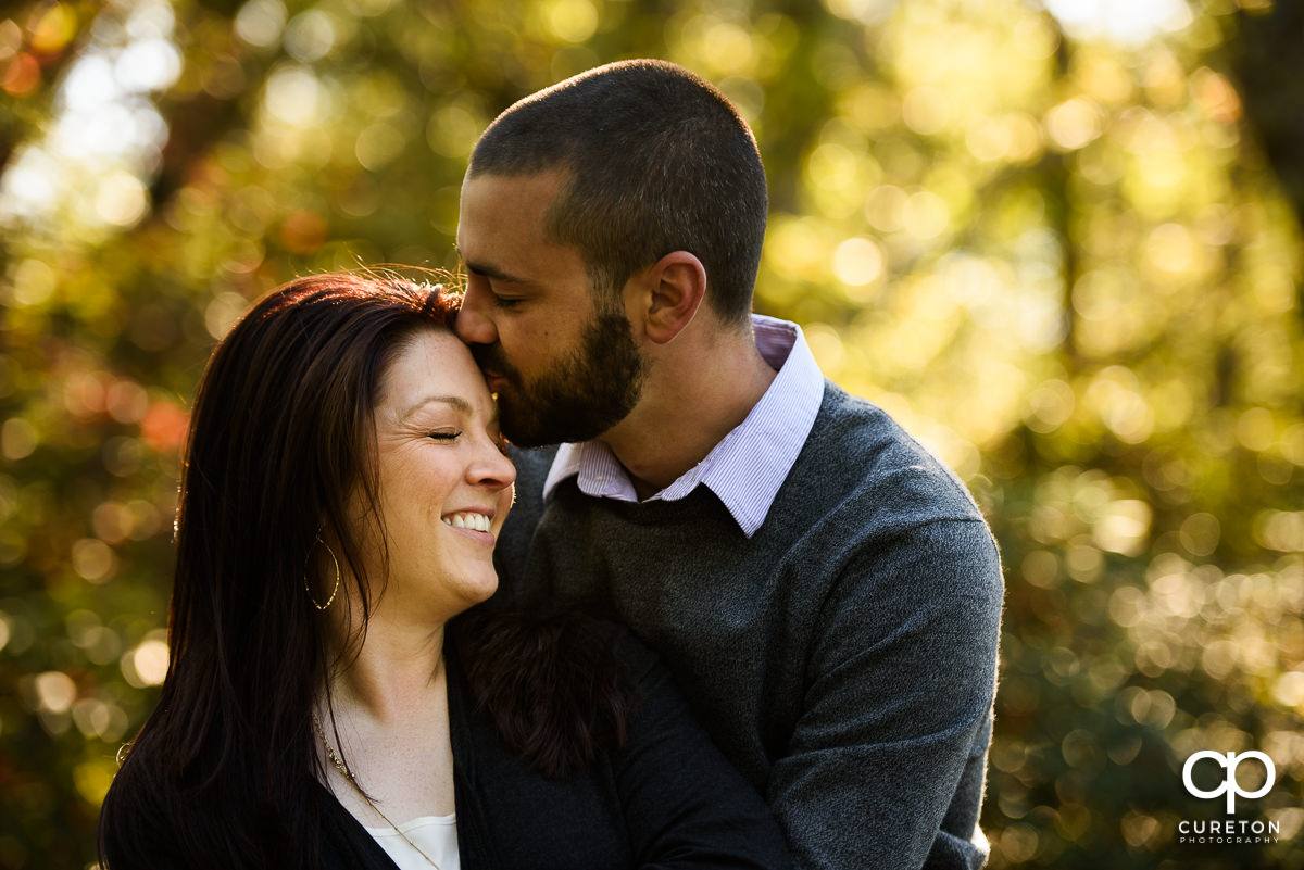 Man kissing his future wife on the forehead.