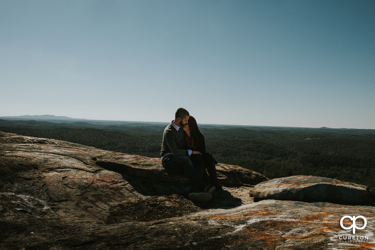 Man and woman sitting on Bald Rock at the end of their engagement session.