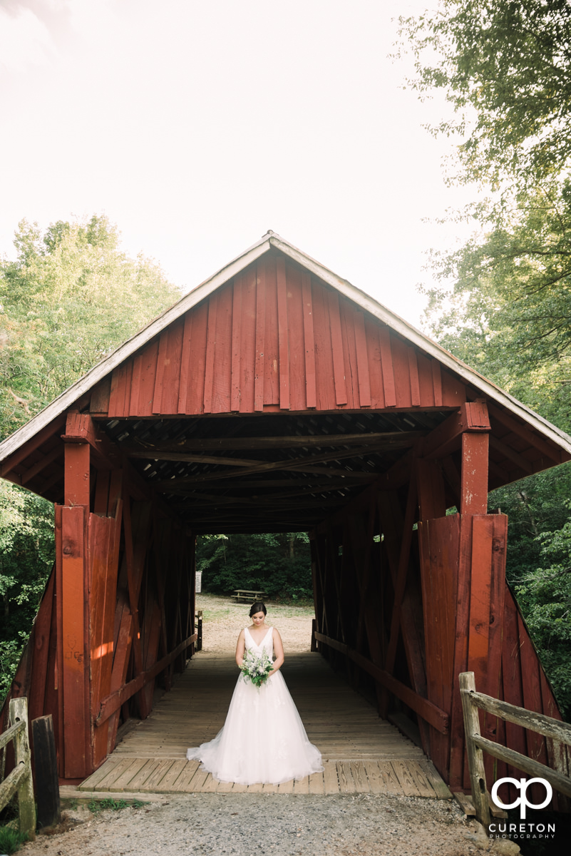 Bride in front of a covered wooden bridge.