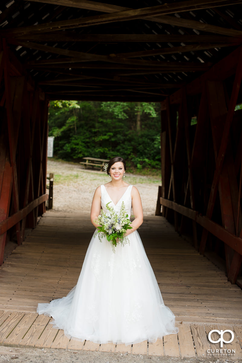 Bride standing in a covered wooden bridge.