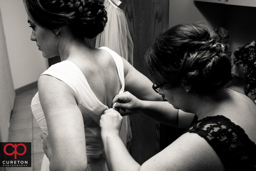 Bridesmaid helping bride with her dress.