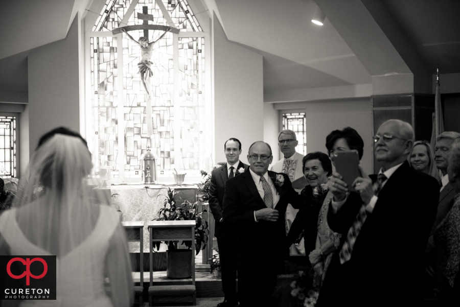 Groom sees his bride for the first time walking down the aisle.