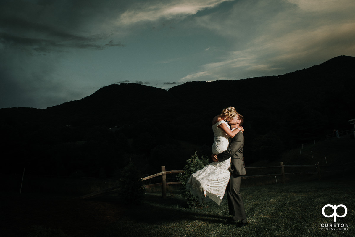 Groom lifting his bride in the air at sunset in the mountains after their wedding at Chestnut Ridge in Canton,NC.