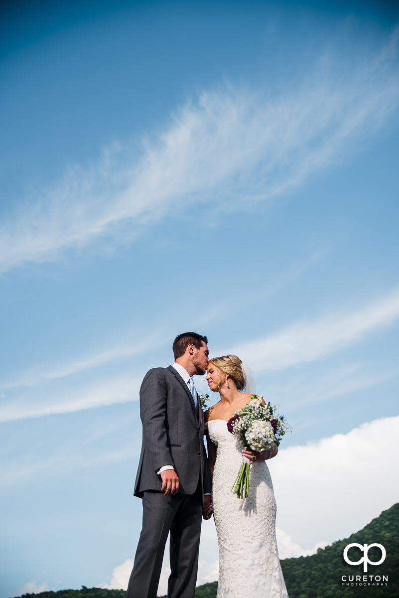 Groom kissing his bride on the forehead at their wedding at Chestnut Ridge.