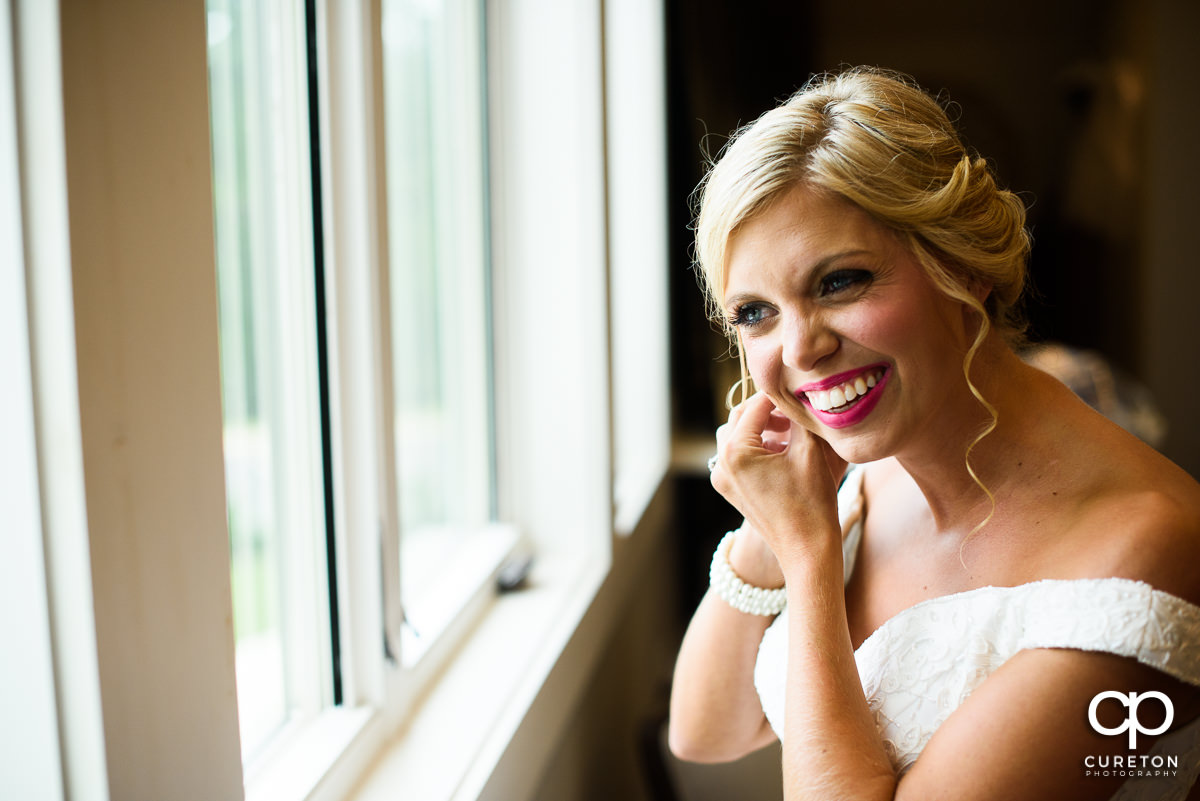 Bride putting her earrings in.