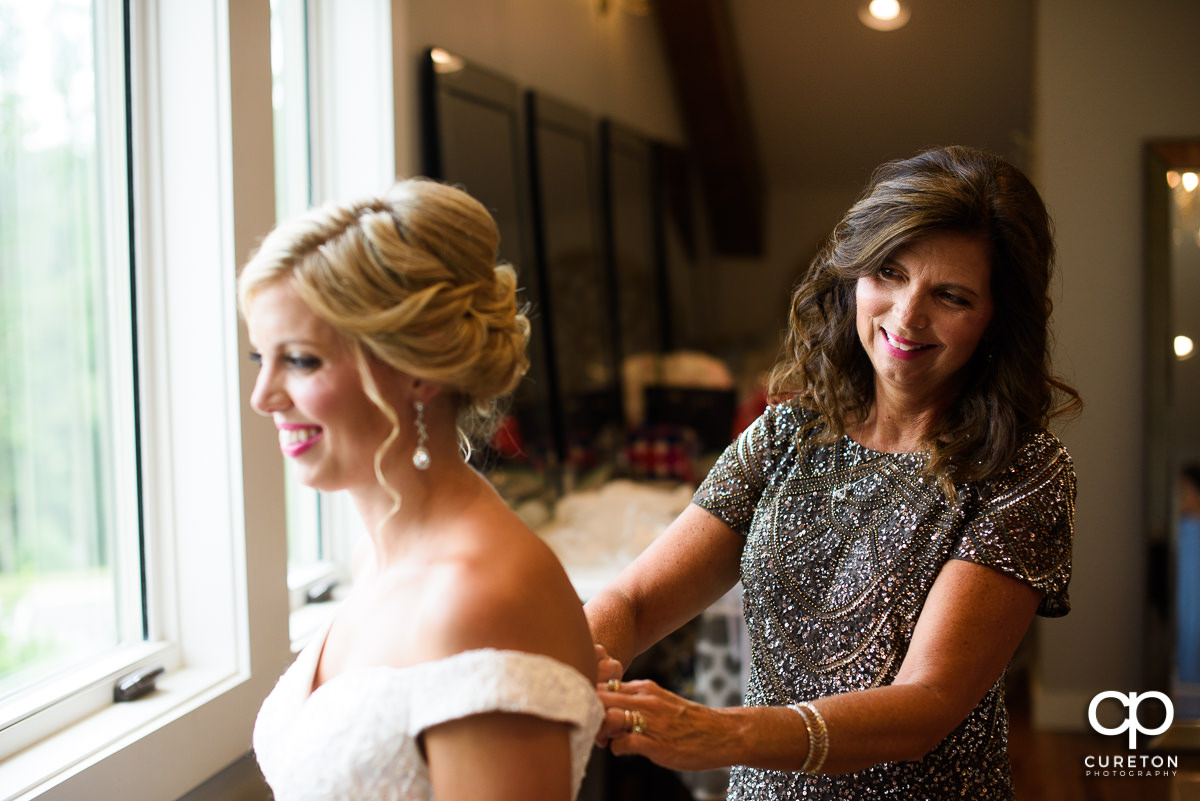 Bride's mother helping her into her dress in the bridal suite at Chestnut Ridge Events.
