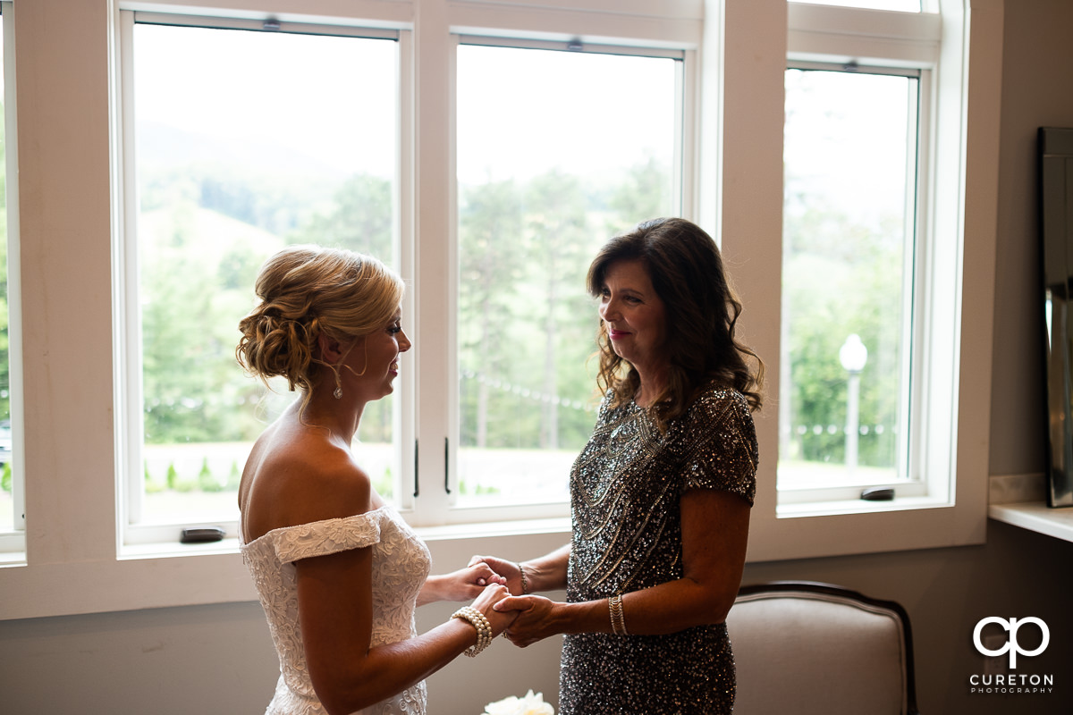 Bride and her mother holding hands.