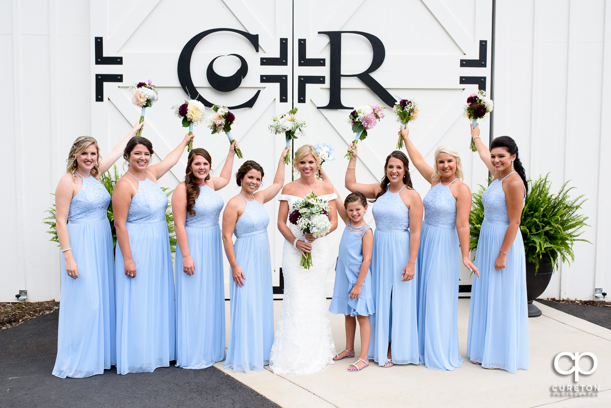 Bridesmaids holding their flowers in the air.