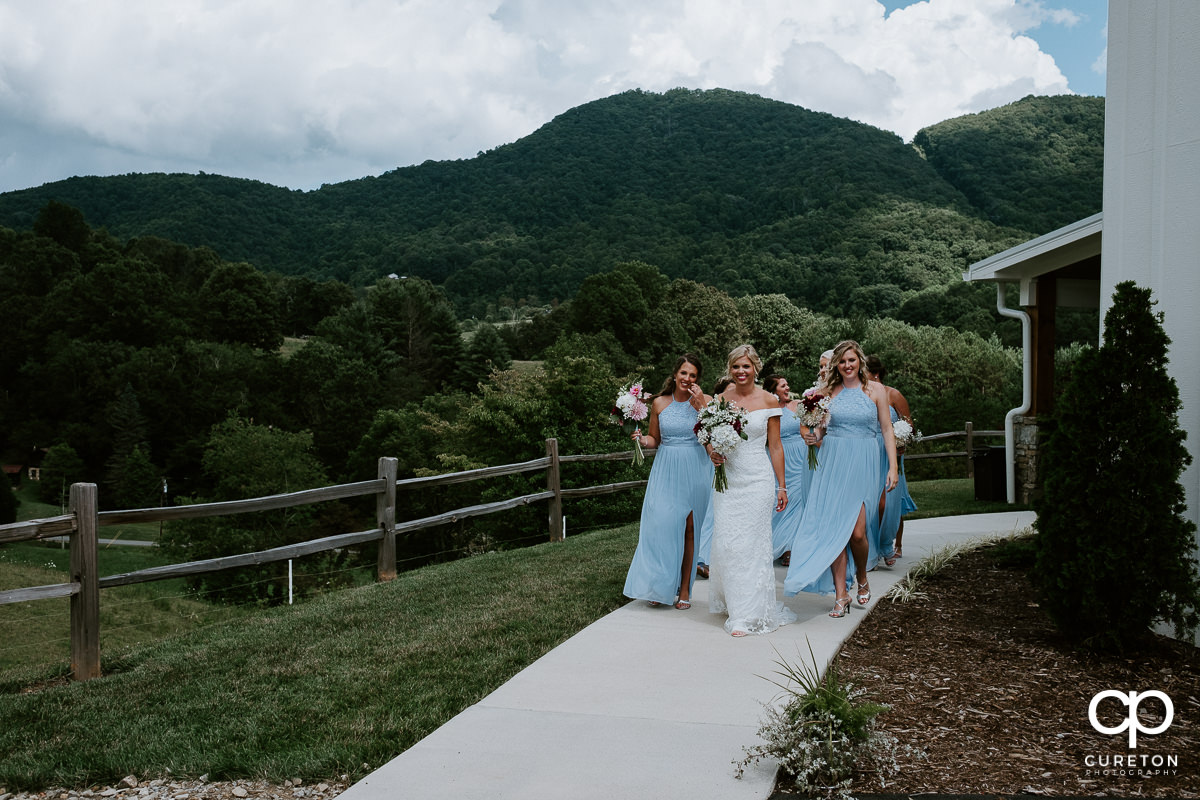 Bride and her bridesmaids walking down a path with the mountains to their backs.
