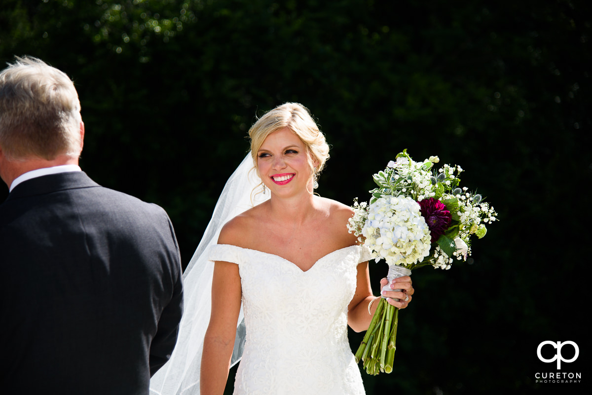 Bride smiling holding her flowers before the wedding ceremony.