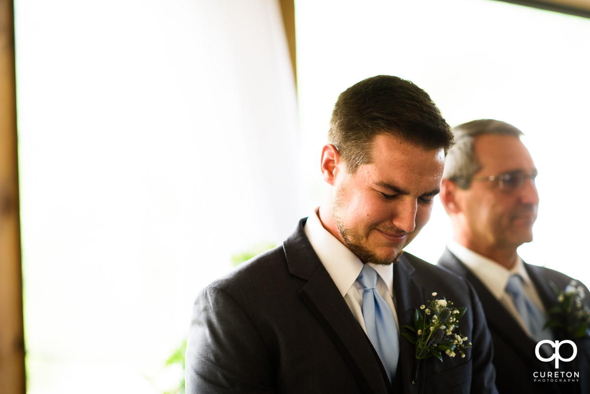 Groom tearing up as he sees his bride walking down the aisle.