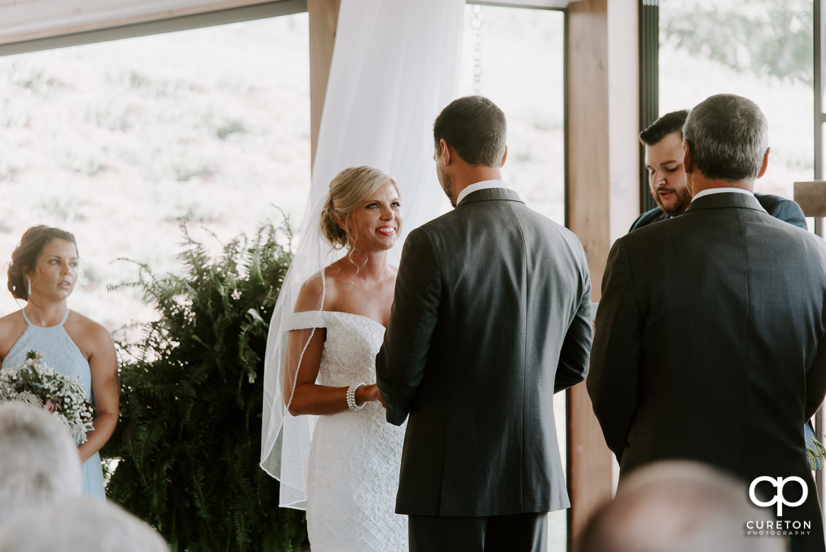 Bride smiling at her groom during the wedding ceremony.