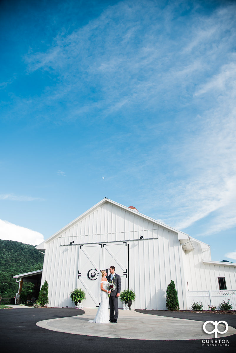 Bride and groom in front of the white barn at Chestnut Ridge in Canton,NC.