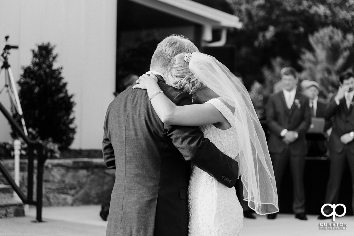 Bride laying her head on her dad's shoulder as they share a dance at the reception.