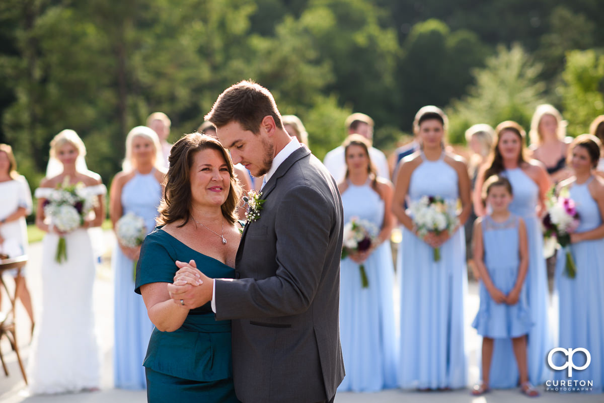 Mom smiling at her son as they share a dance at the reception.