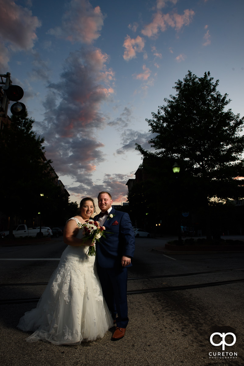 Bride and groom standing in Main St. at sunset after their wedding at the Old Cigar Warehouse in downtown Greenville,SC.