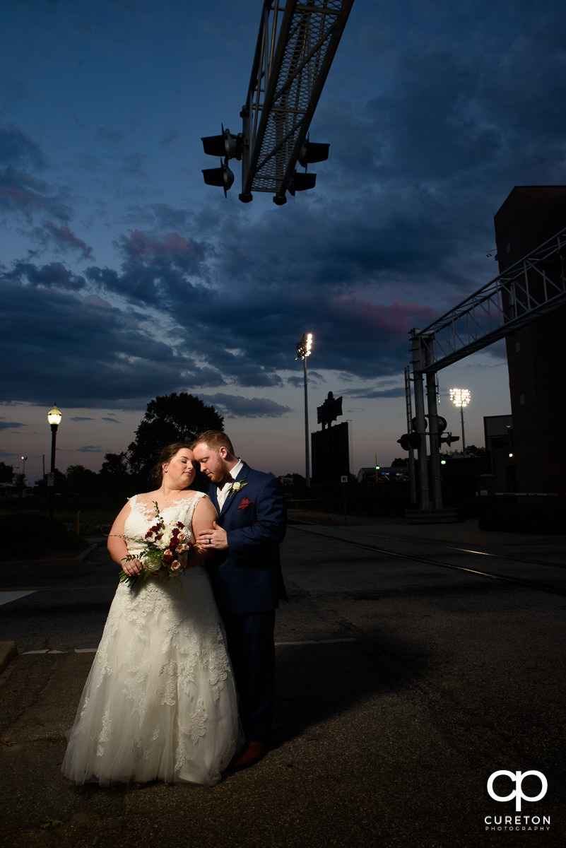 Groom snuggling with his bride at sunset after their wedding at the Old Cigar Warehouse in Greenville,SC.