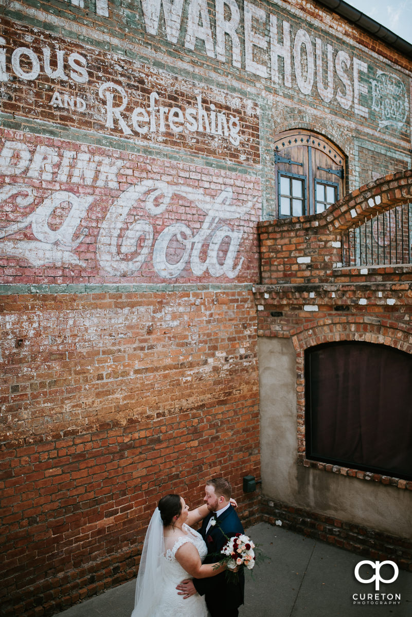 Bride and groom dancing in front of the Coca-Cola mural at The Old Cigar Warehouse in downtown Greenville before the wedding ceremony.