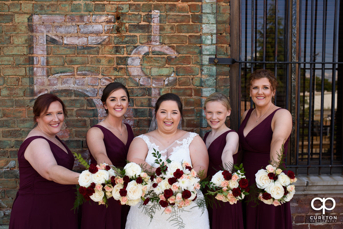 Bride and her bridesmaids showing their flowers.