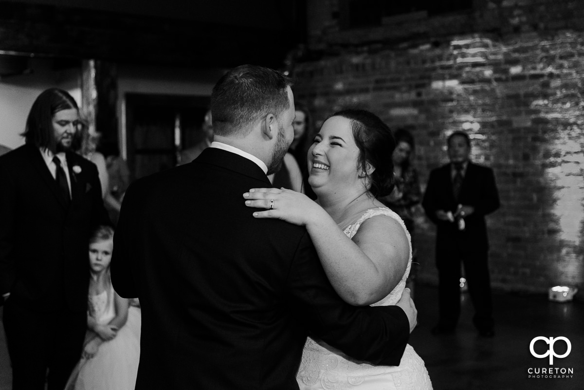 Bride laughing during the first dance at the wedding reception in Greenville at The Old Cigar Warehouse.