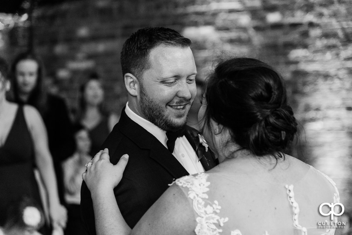 Groom smiling at his bride during their first dance at the wedding reception in Greenville at The Old Cigar Warehouse.