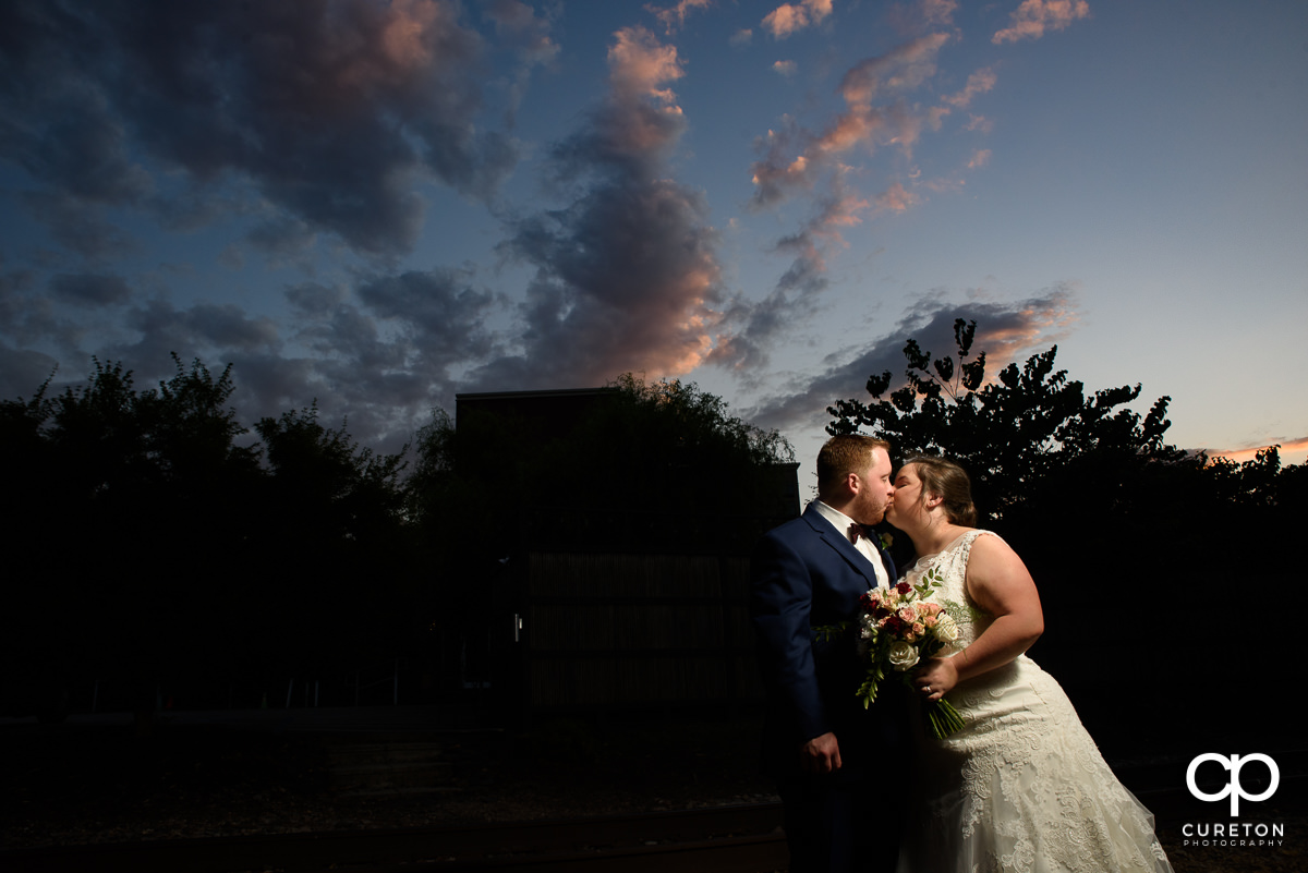 Bride and groom kissing at sunset at the wedding reception in Greenville at The Old Cigar Warehouse.