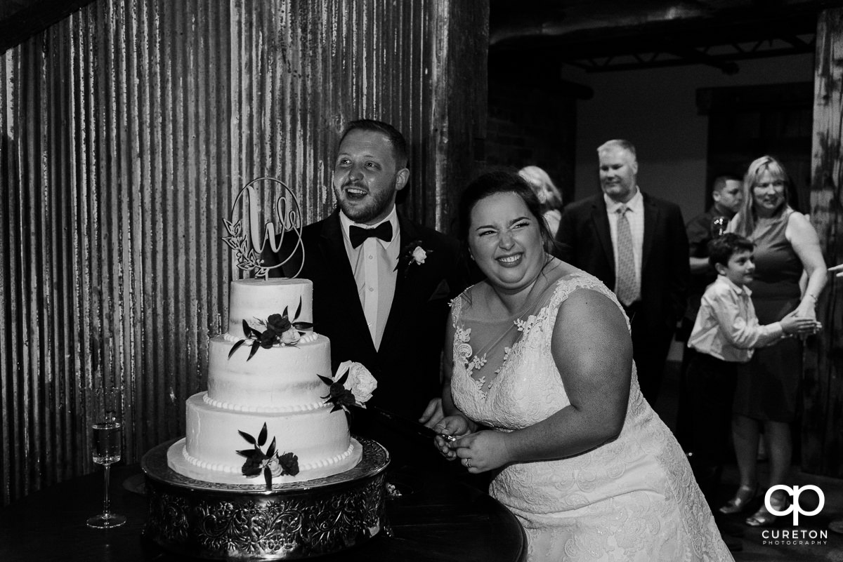 Bride and groom laughing while cutting the cake.