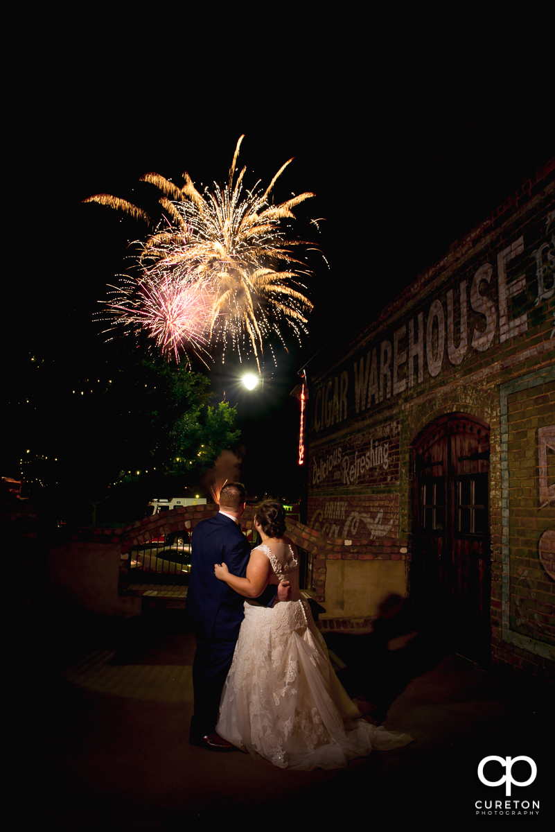 Bride and groom watching the fireworks show in downtown Greenville from the deck of The Old Cigar Warehouse at their wedding reception.