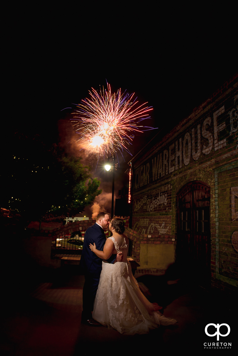 Bride and groom watching the fireworks show in downtown Greenville from the deck of The Old Cigar Warehouse at their wedding reception.