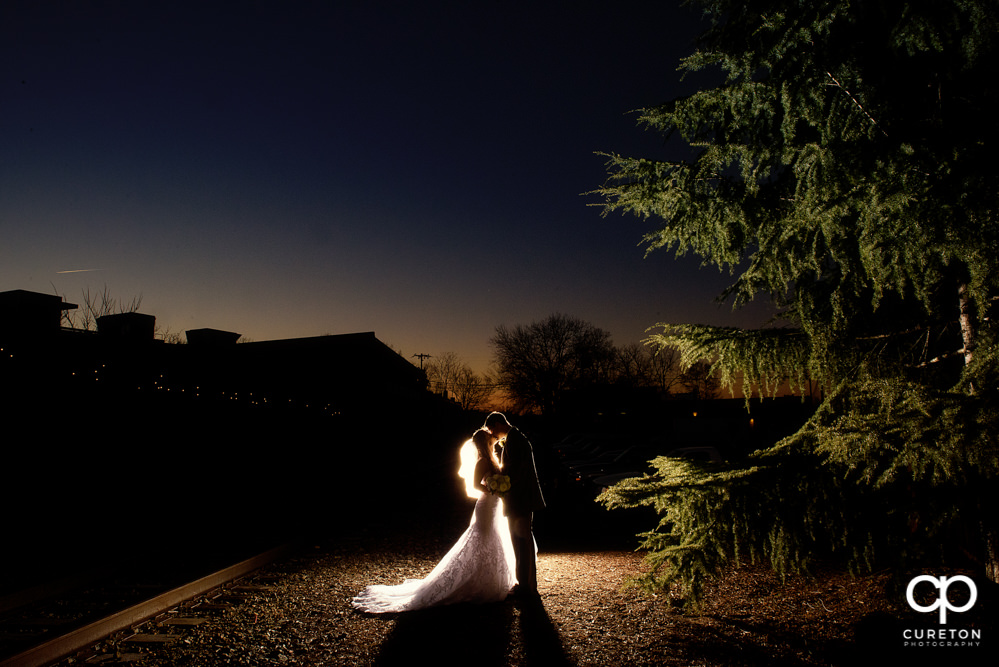 Bride and Groom kissing at sunset after their wedding at The Old Cigar Warehouse in downtown Greenville,SC..