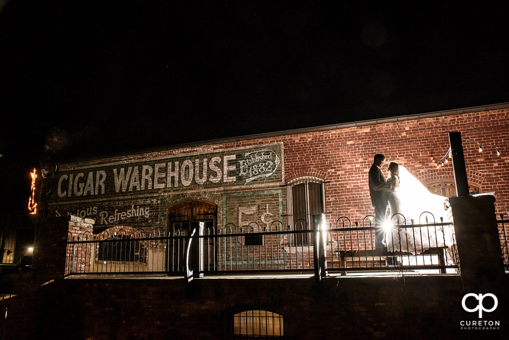 Backlit photo of a newlywed couple on the deck of The Old Cigar Warehouse.