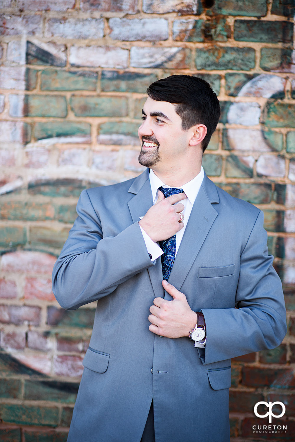 Groom adjusting his tie.