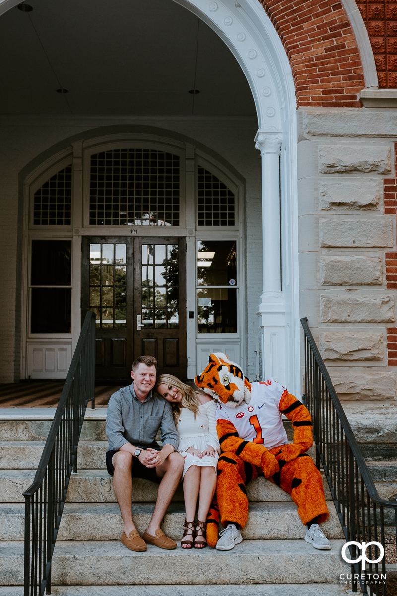 Engaged couple leaning on each other and the Clemson Tiger during an engagement session with the mascot.