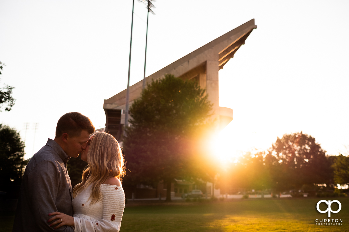 Man kissing his fiancee in front of Death Valley stadium in Clemson.