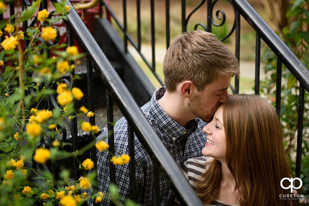 Future groom kissing his bride on the forehead during a Botanical Garden Engagement session.