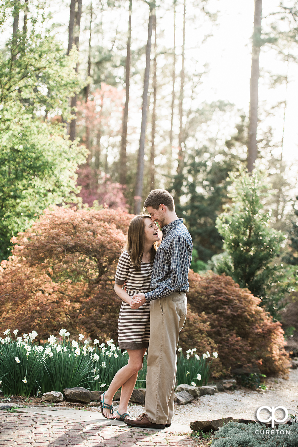 Engaged couple laughing during an engagement session at the Botanical Gardens in Clemson.