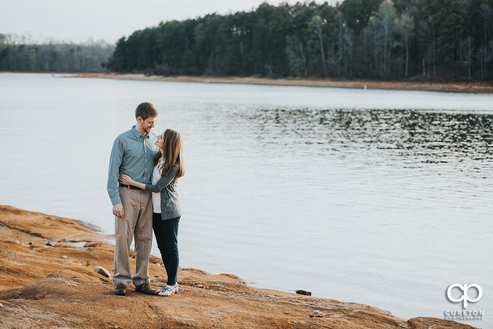 Couple walking by the lake during an engagement session at the lake in Clemson.