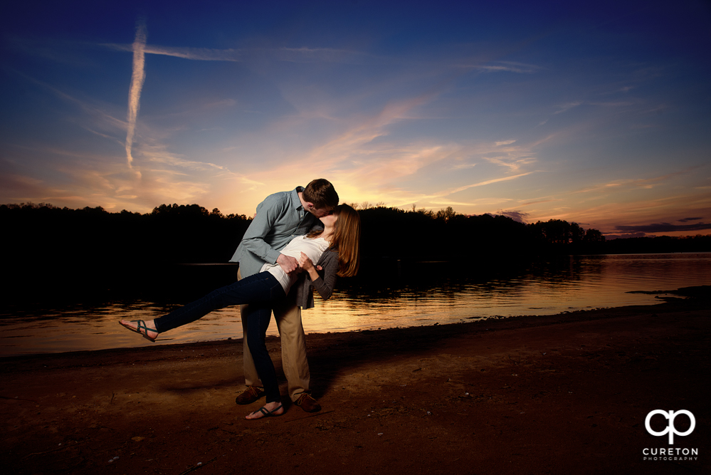 Engaged couple dipping during an engagement session at the lake in Clemson.
