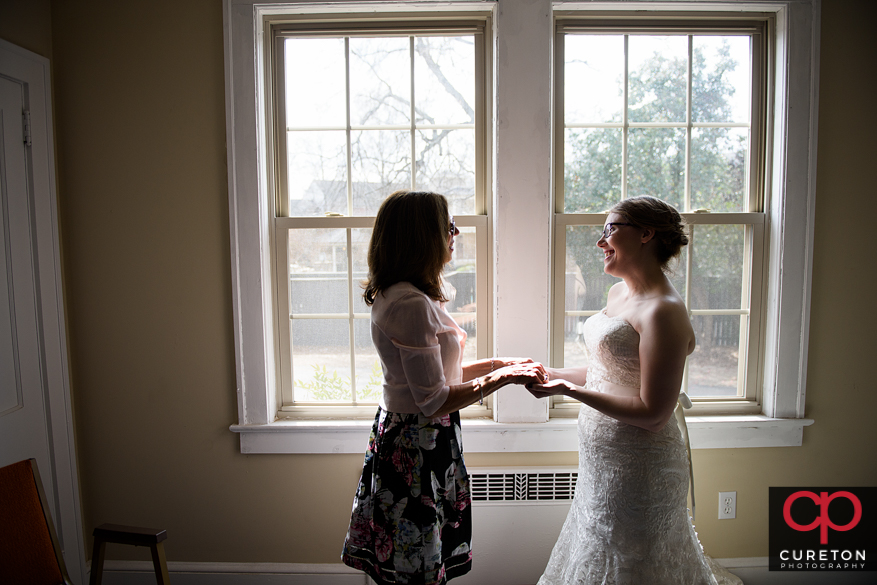 Bride and mother standing in the window light.