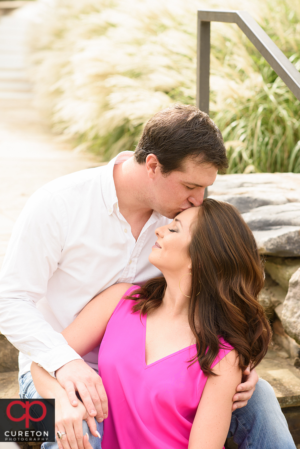 Man kissing his fiancee on the forehead.