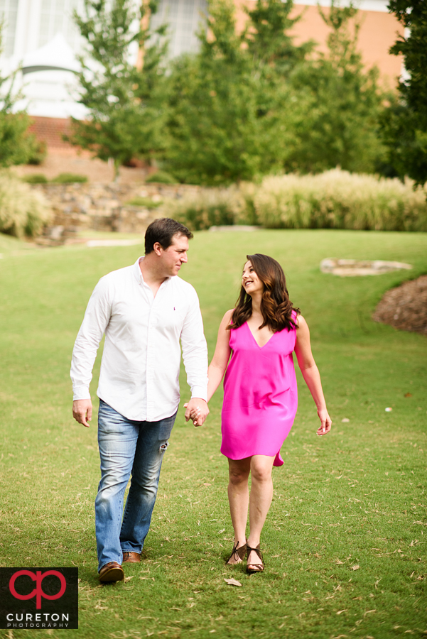 Engaged couple walking through the park.