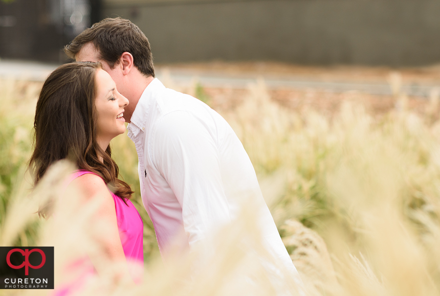 Groom whispering something into his fiancee's ear.