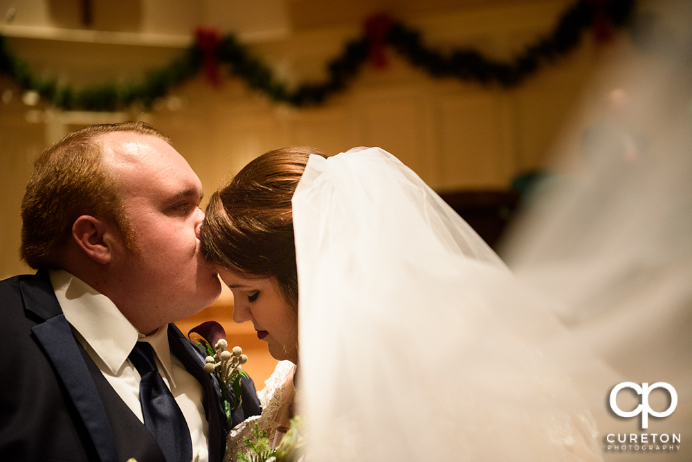Groom kissing his bride on the forehead after their Spartanburg wedding.